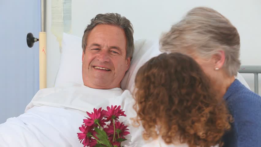 Adorable girl paying her grandfather a visit with her grandmother at the hospital