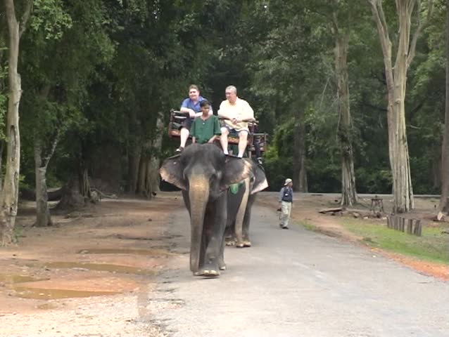 Overweight tourists riding Elephant in the Angkor complex, Cambodia.