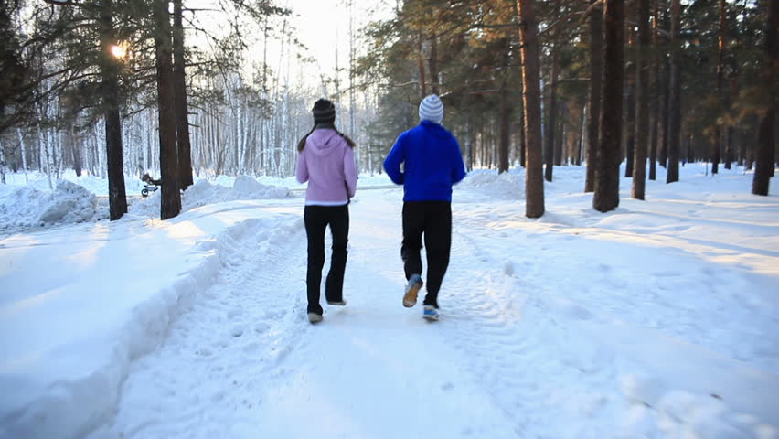 HD steadycam: a girl and a guy jogging in the forest in winter. Montage. 