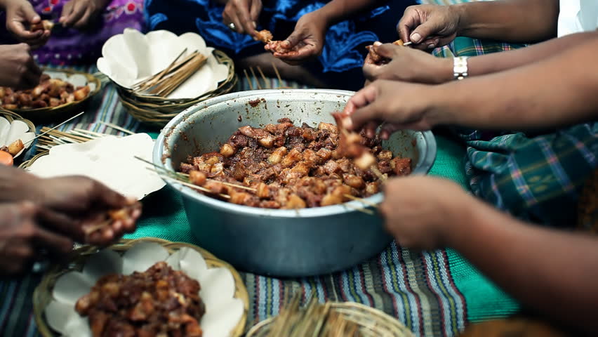 Group of indigenous balinese people sitting in a group and preparing meat for traditional sate meal, atmospheric shot with selective focus / HD1080 / 30fps
