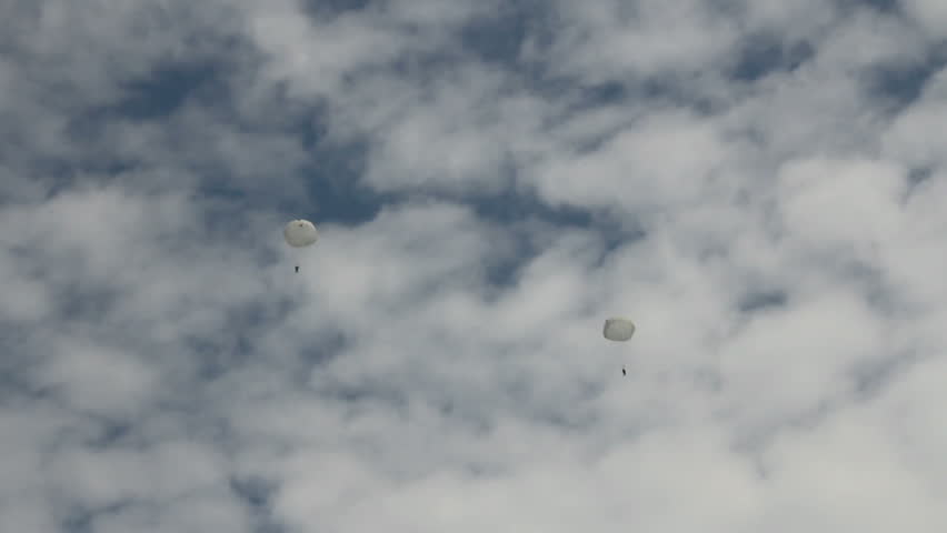 Paratroopers jump on background cloudy sky
