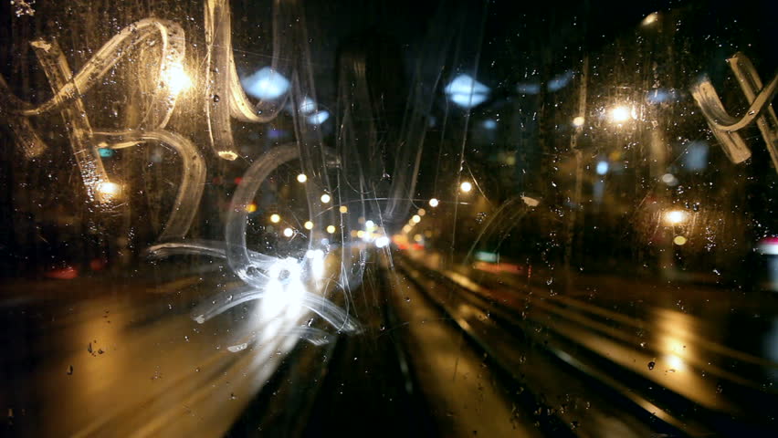 Tram's rear window view. Tram passes through tunnel. Cold rainy weather cityscape. Steamy window. Night time. Focus on window. 