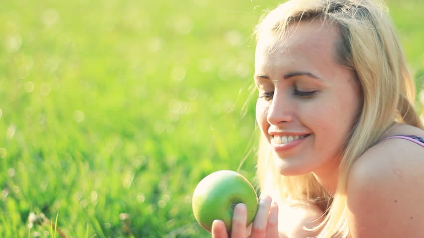 Attractive happy woman biting fresh apple outdoor