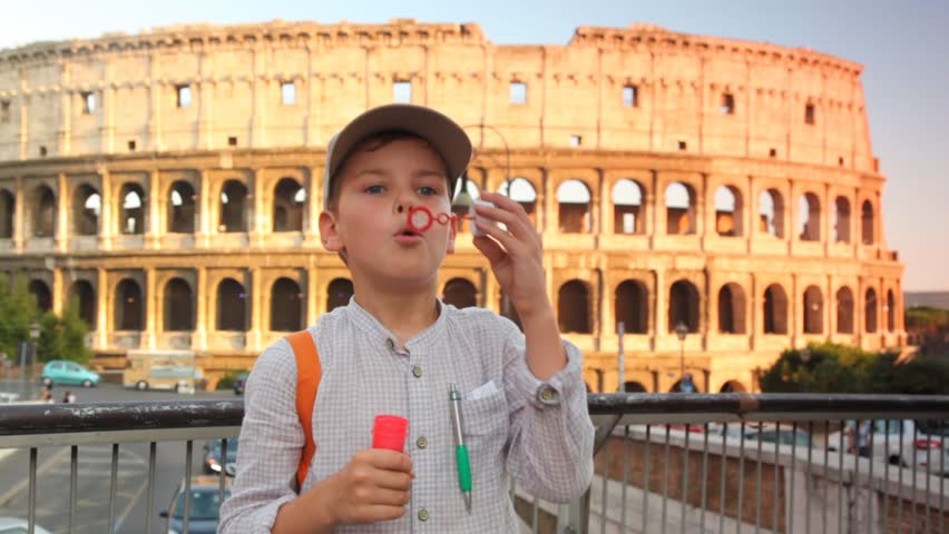 boy blow soap bubbles on pedestrian crossing on background of Colosseum in Rome