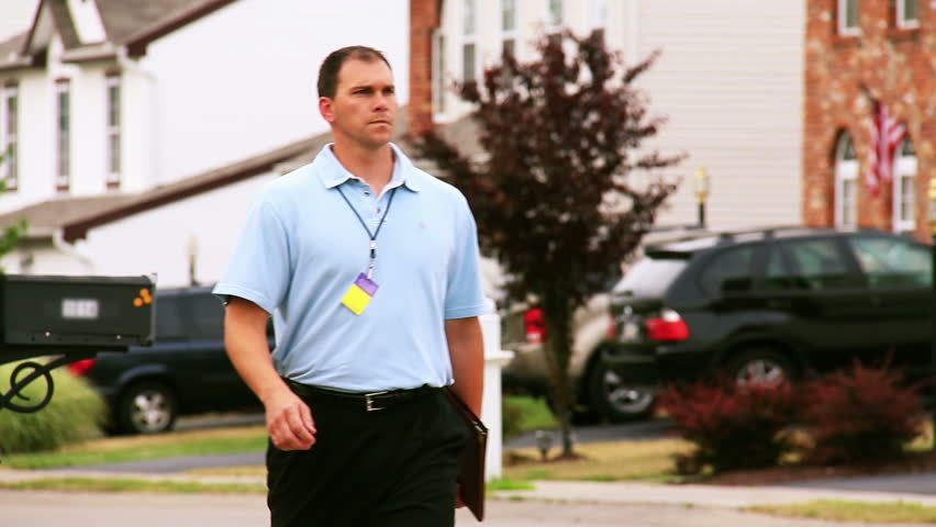 A door to door salesman walks in a neighborhood.