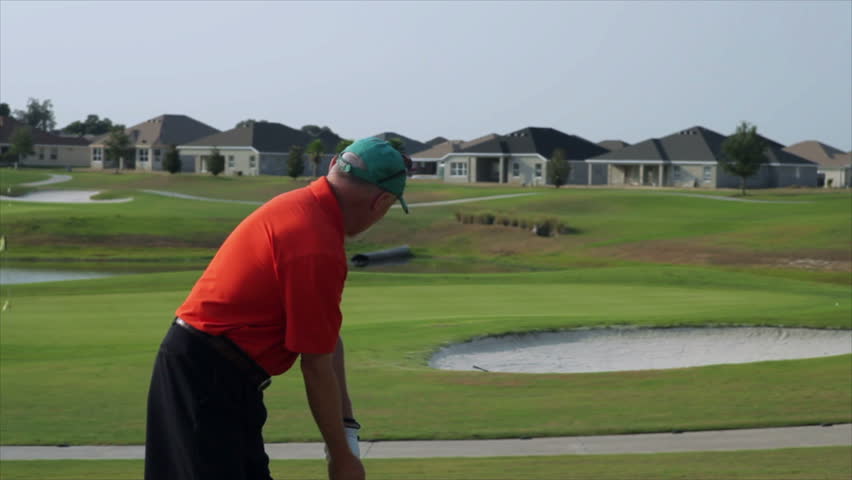 A golfer grabs his shoulder and winces in pain during a golf swing.