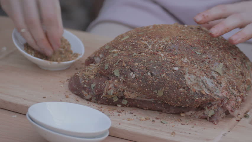 EDIT MULTICAM VIDEO Woman Sprinkling and smearing all sides of fat pork by the remaining mixed kitchen spicy herbs on wooden chopping board. 