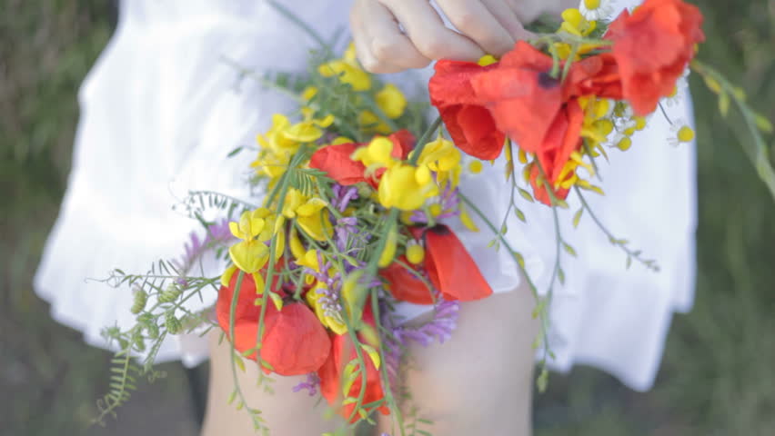 Young woman makes bouquet of flowers in forest