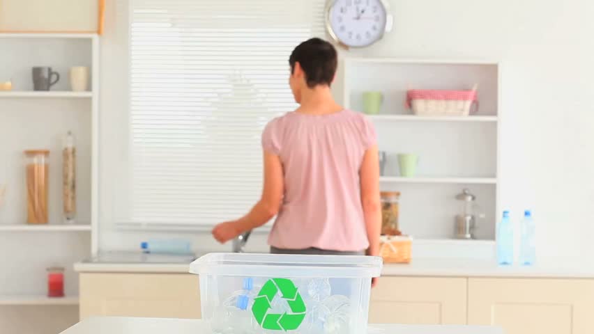 Woman recycling her waste in her kitchen