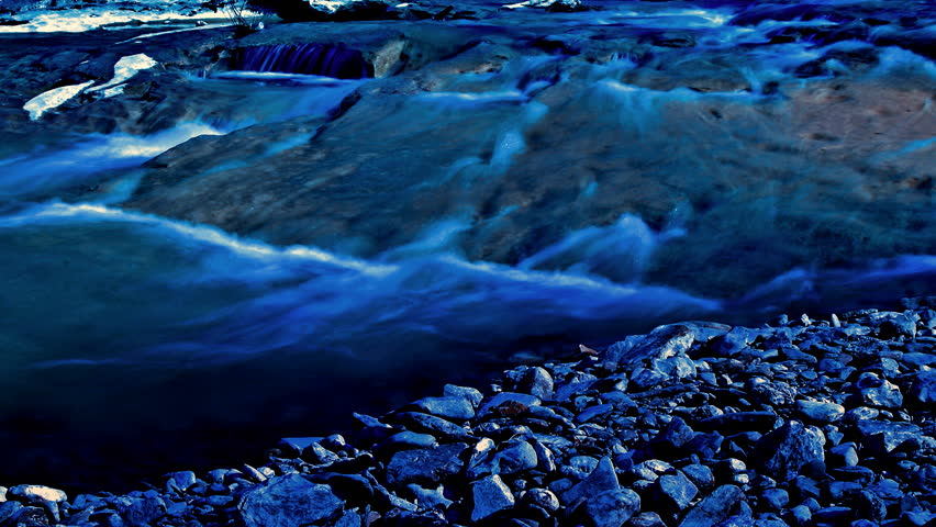 Blue river passing in cascades on the pebble coast 