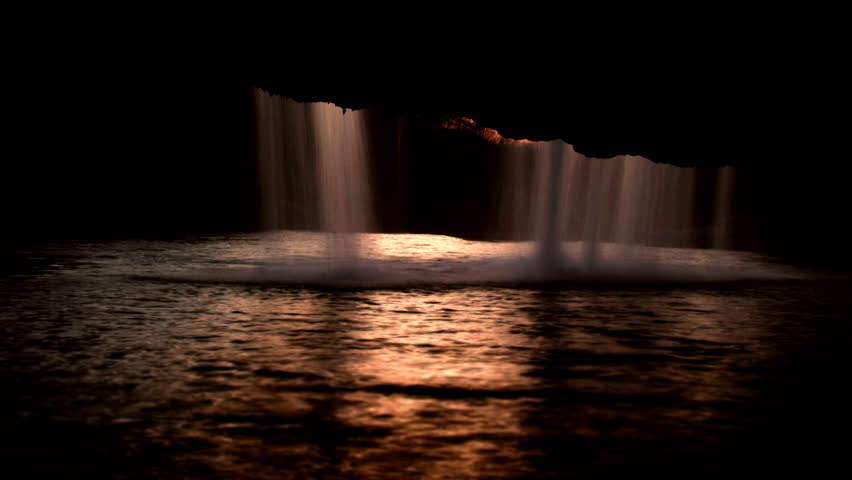 Waterfall falling into the golden lake in Zarecki krov, shot from the cave