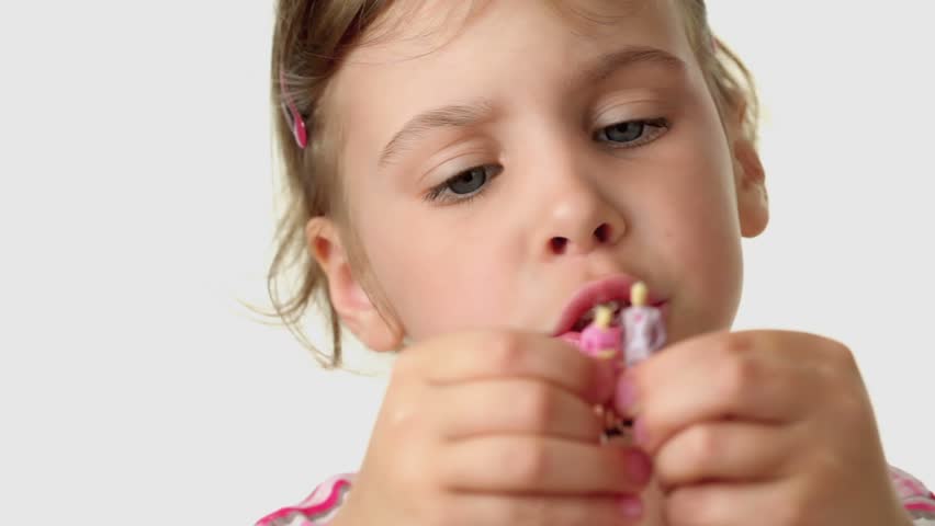 Girl holds couple toy people miniature of man and woman, she plays them and says something