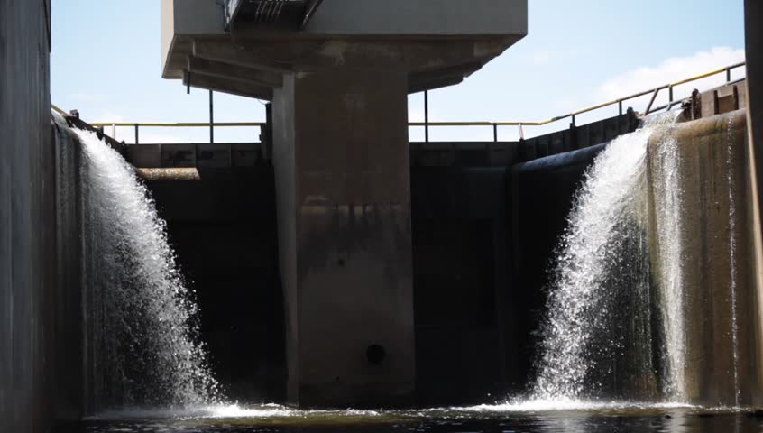 A small dam is fed by a reservoir.