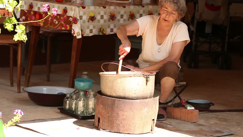 Farm tomato juice cooking. Old woman mixes the juice. 