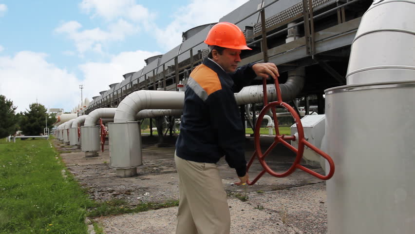 worker comes and twists opening valve on unit of cooling gas compressor station