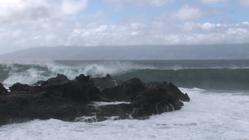 Rocky cove shoreline on island of Maui in Hawaii.  Beautiful water with cliff and trees overlooking water. Waves splashing on rocks, scenic, relaxing and calm, tropical. Water splash on lens.