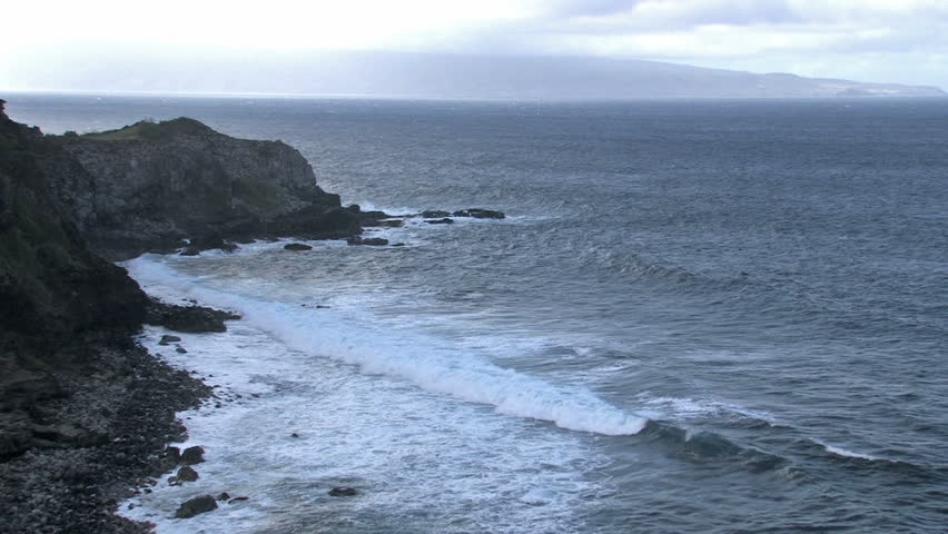 Rocky shoreline on the island of Maui in Hawaii.  Rough surf splashing against rocks. Scenic, relaxing and calm, beautiful tropical video. Island of Molokai in distance.