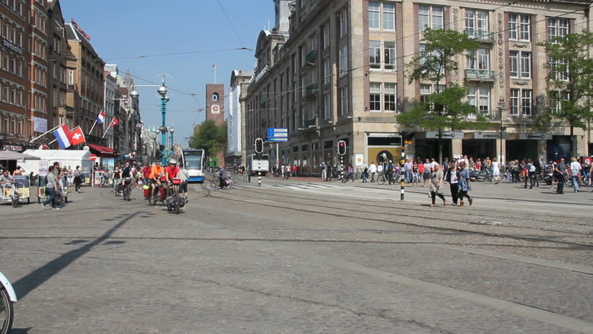 AMSTERDAM, HOLLAND - AUGUST 1: Tram and cyclists drive along Dam square, with tourists crossing the street, on August 1, 2011 in Amsterdam, Holland.