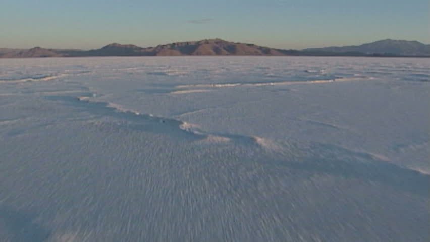 Camera flies low over eerie, dramatic moonscape salt flats.