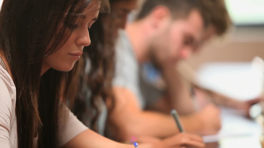 Close up of students writing in an amphitheater