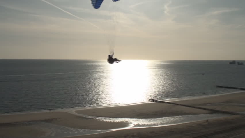 Parasailer sailing over the dunes and the beach along the coast of the province Zealand in the Netherlands when the sun sets. 