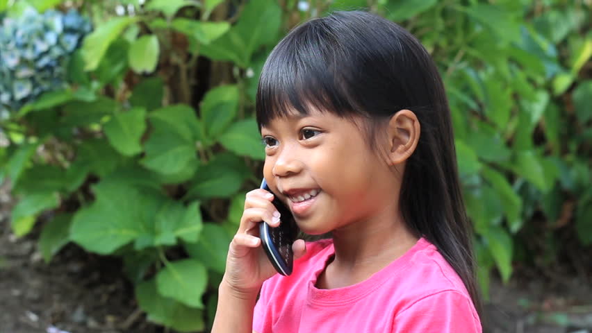 A cute little Asian girl talks to her daddy on her mommy's cell phone.