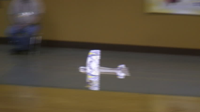 Radio-controlled foam model airplane performing aerobatic tricks at the competition venue