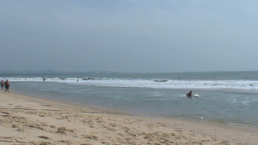 vendors carry their goods on a beach in Cambodia