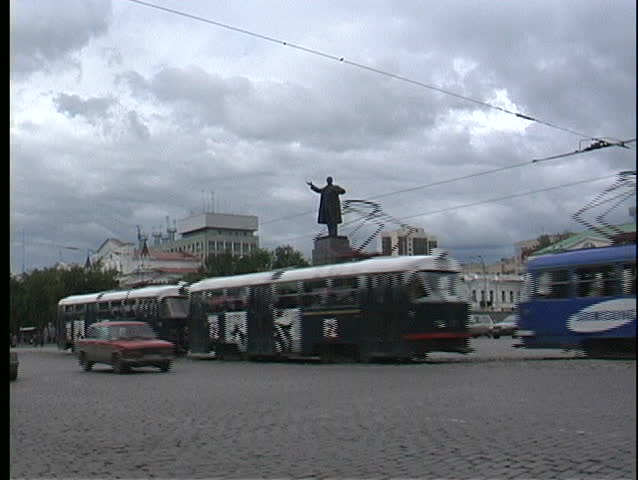 RUSSIA - CIRCA 2006: A pan of a busy Russian street with busses and vehicles passing the Yekaterinburg Lenin Statue circa 2006 in Russia.