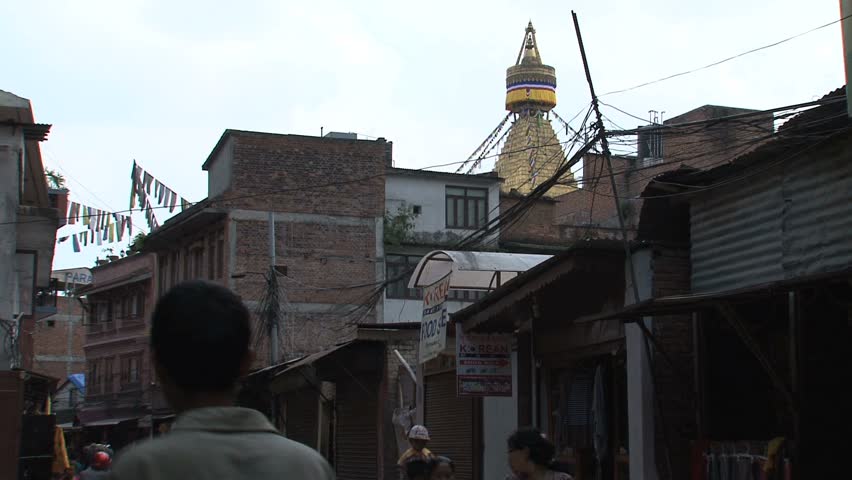 KATHMANDU - CIRCA 2010: People circulate through the city with the Boudhanath Stupa temple in the background circa 2010 in Kathmandu.