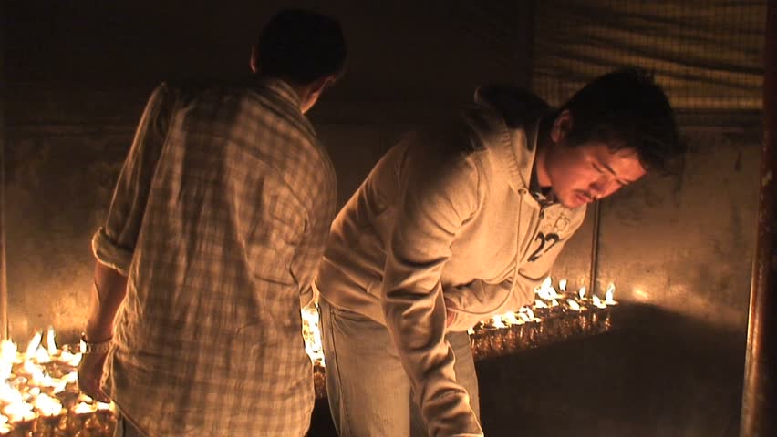 People lighting candles inside a temple in nepal