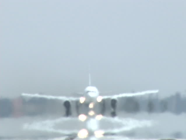A plane takes off and leaves its reflection on the wet pavement.