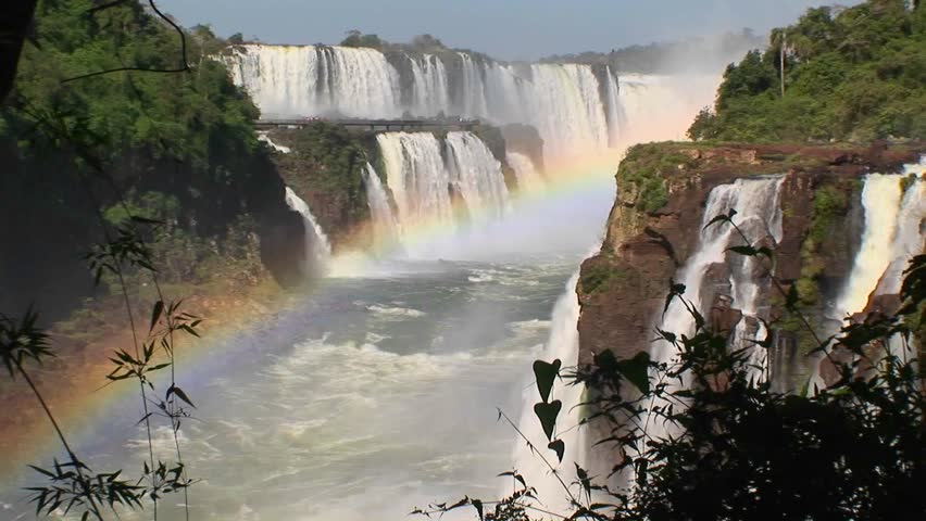 A zoom into Iguacu Falls with a rainbow in the foreground.