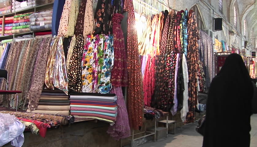 IRAN - CIRCA 2010: Women in chadors pass carpets in a bazaar circa 2010 in Iran.