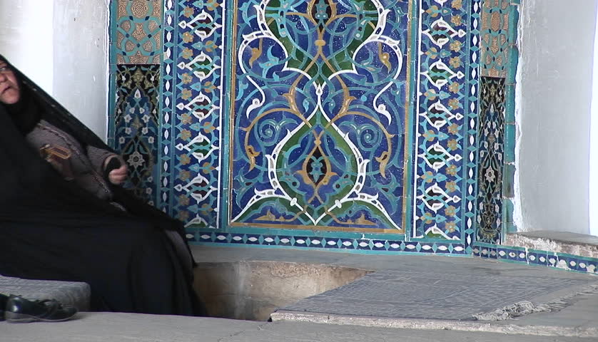 IRAN - CIRCA 2010: A woman wearing a chador sits before a carpet in a bazaar circa 2010 in Iran.