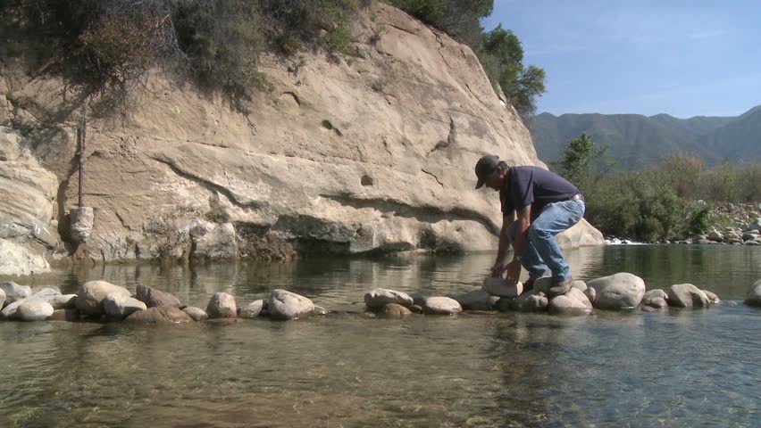 OJAI, CA - CIRCA 2009: Man removing rocks from a fish barrier on the Ventura River Preserve circa 2009 in Ojai, California. 