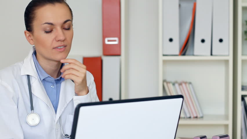 Overworked female doctor sitting at the desk and yawn