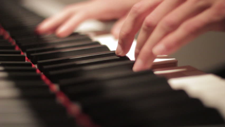 Two hands playing a gentle piece on a beautiful grand piano. A recording of the reflection using a shallow depth of field.