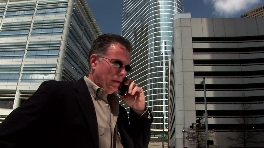 business man on his cell phone in front of some large office buildings