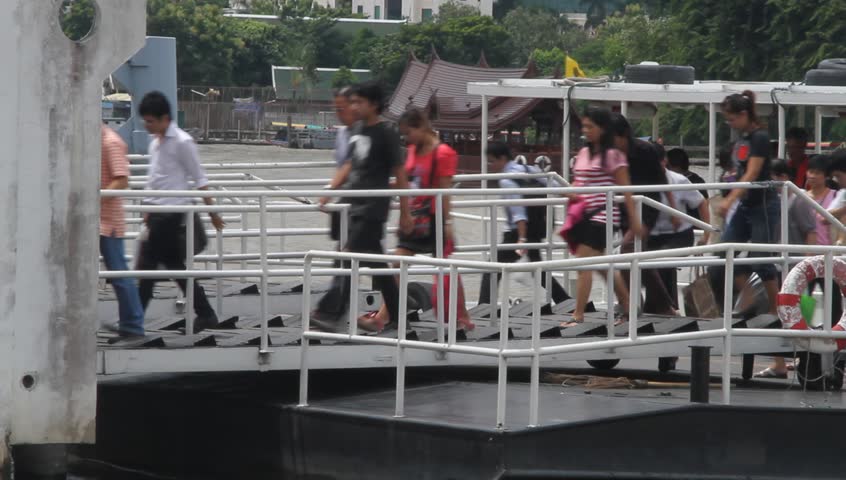 BANGKOK, THAILAND - SEPTEMBER 19: Tourists walk from boat to pier on the Chao Phraya river, September 19, 2011 in Bangkok, Thailand. The Chao Phraya is a major river in Thailand, with its low alluvial plain forming the centre of the country.