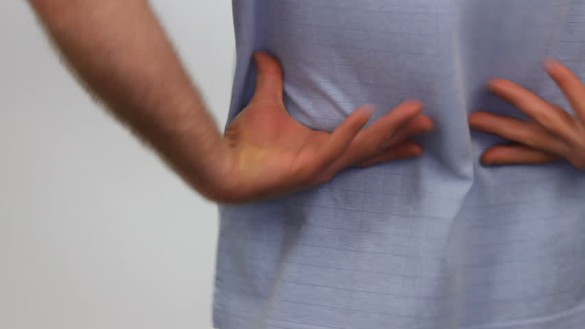 Man giving his low back a quick massage to try and get relief from some back pain.