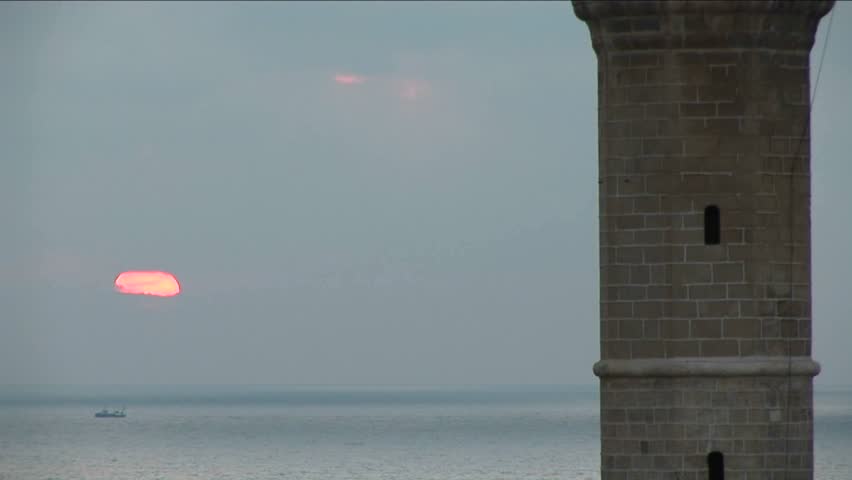 The sun sinks behind the minaret of a mosque in Israel.