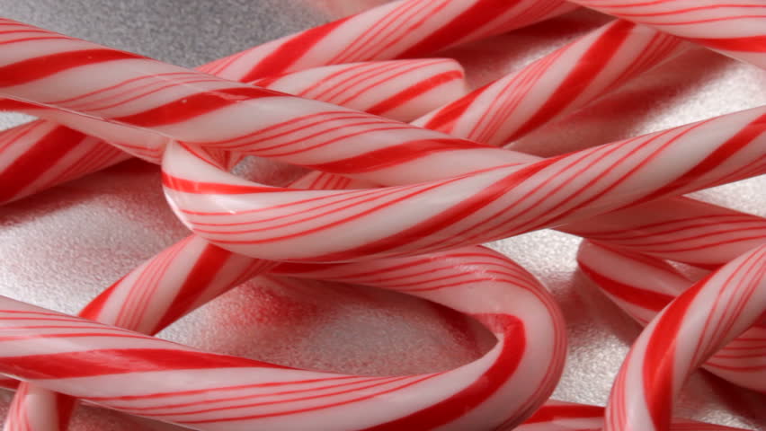Closeup of candy canes moving across the screen, with clear silver background with space for copy