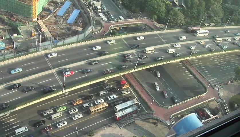 Traffic flows along an overpass and city streets as pedestrians walk around