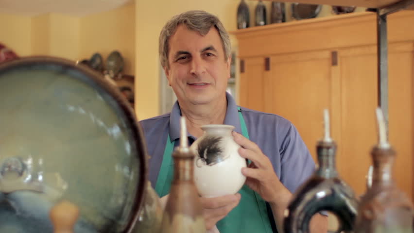 Pottery shop owner holding a vase in his store