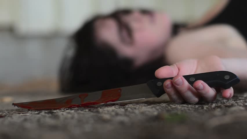 Conceptual footage of a dead woman holding a sharp knife covered with blood.