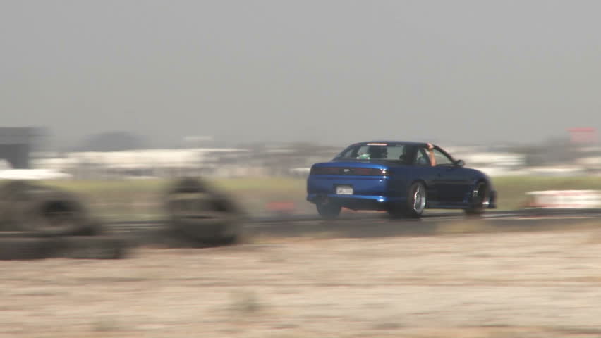 the camera follows a blue car as it glides through a drifting course at Camarillo Airport in Camarillo California.