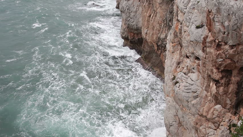 Ocean water Mediterranean waves crashing against rock ledges and rugged coast. Straights of Gibraltar, Europa Point. Mediterranean Sea ocean waves crashing against rock and cliff.