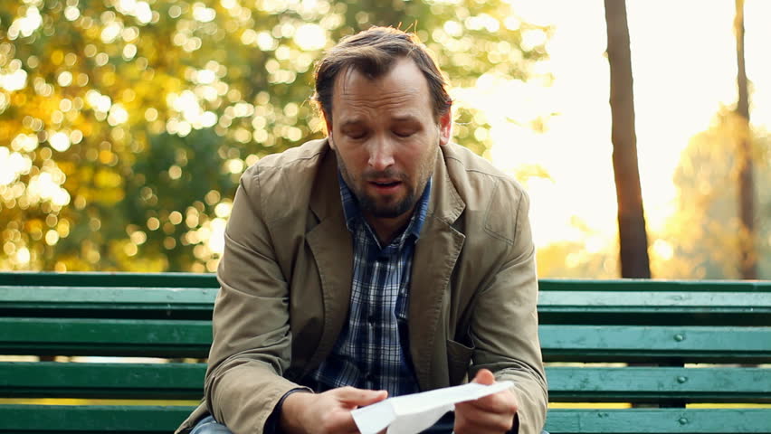 Sick man blowing his nose into tissue, outdoors