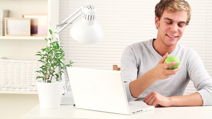 Happy young student browsing the internet and smiling at camera - indoors